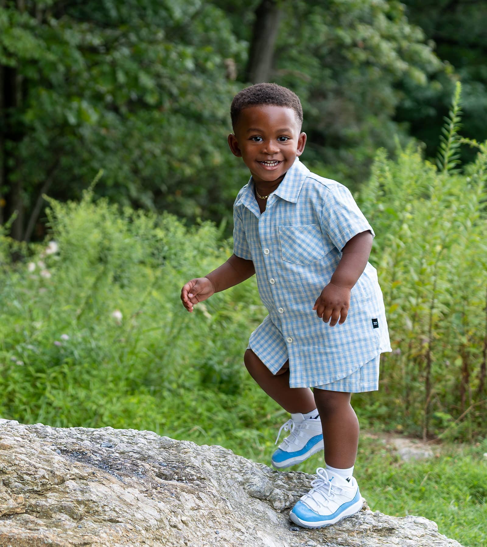 A young boy jumping down off a boulder on a wooded trail in York County
