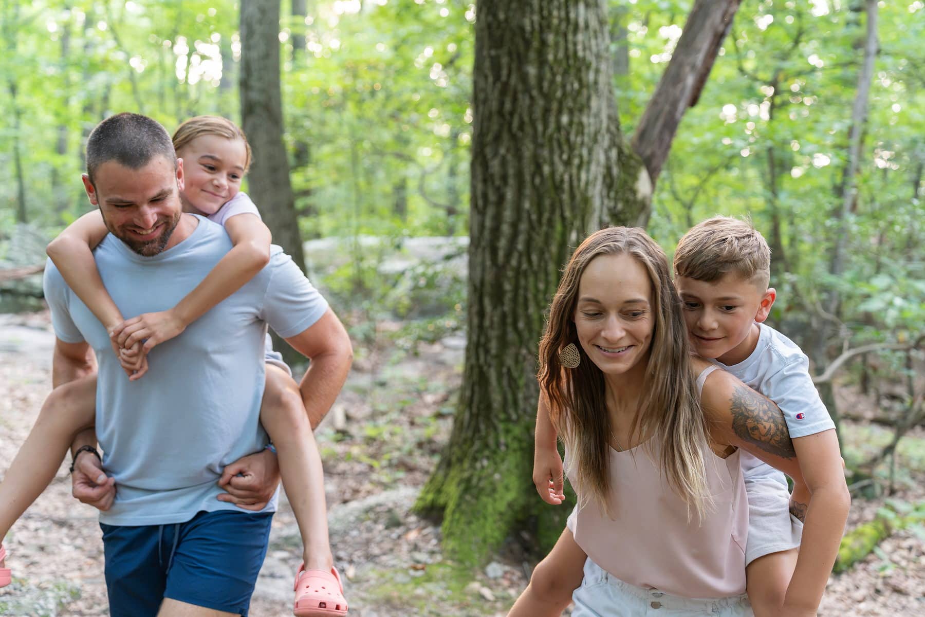 Two sisters racing piggyback down a park trail, both laughing