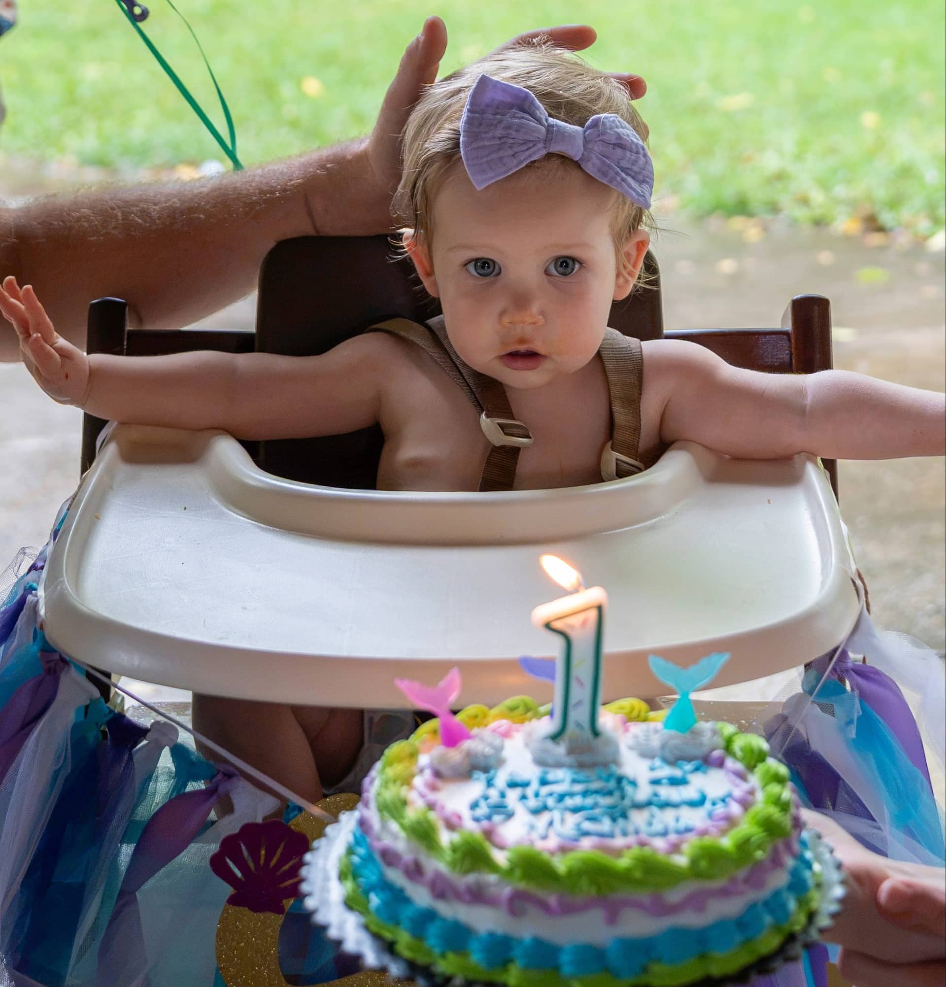 A decorated first birthday cake carried out to the table