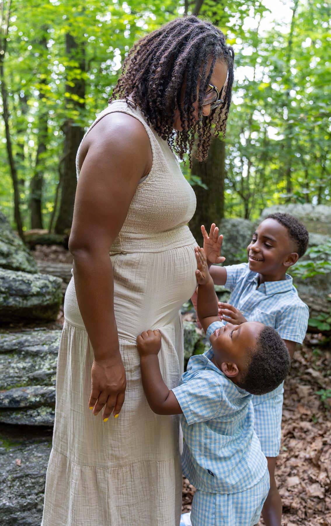 A small boy reaching up to his mother as she leans down to him