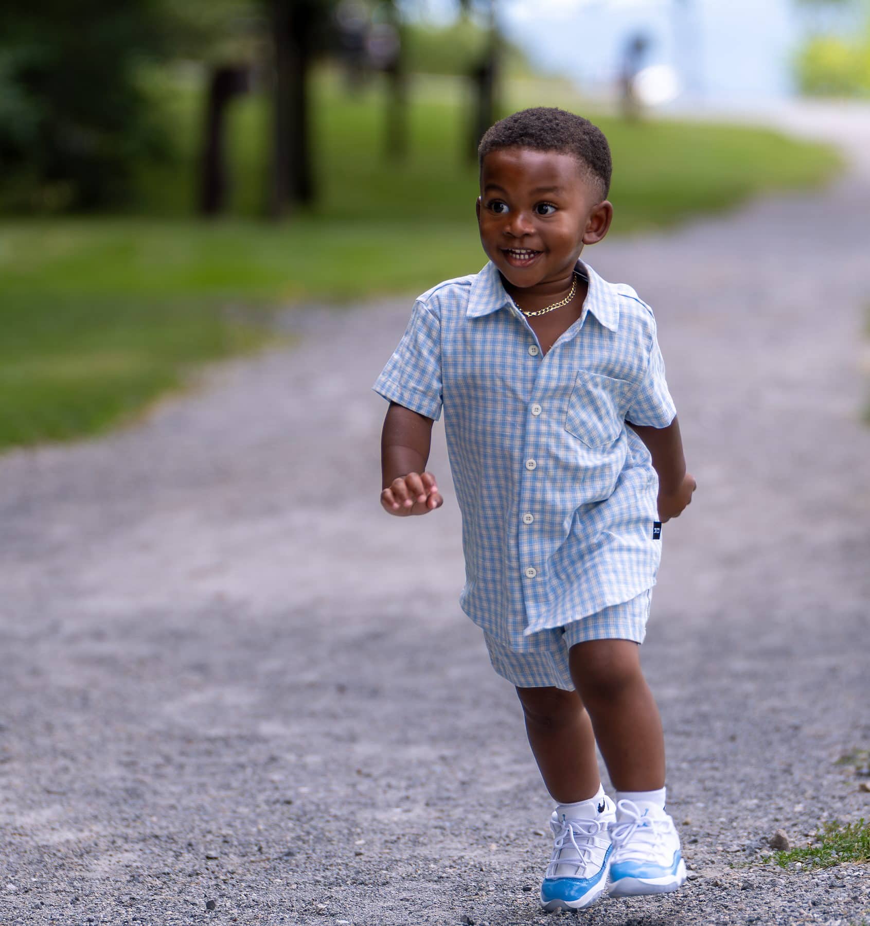A young boy running at full speed toward the camera on a gravel path