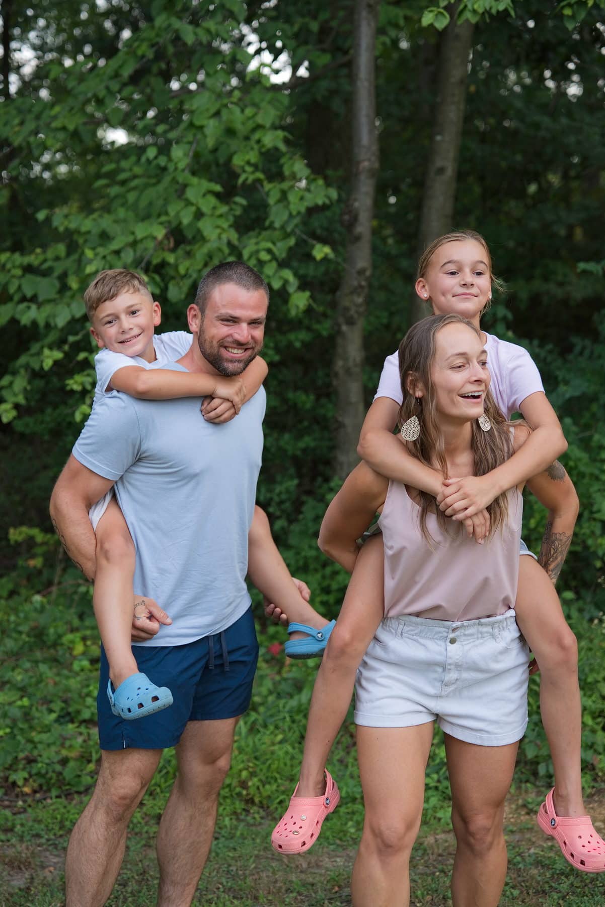 A father laughing with all three of his children climbing on him
