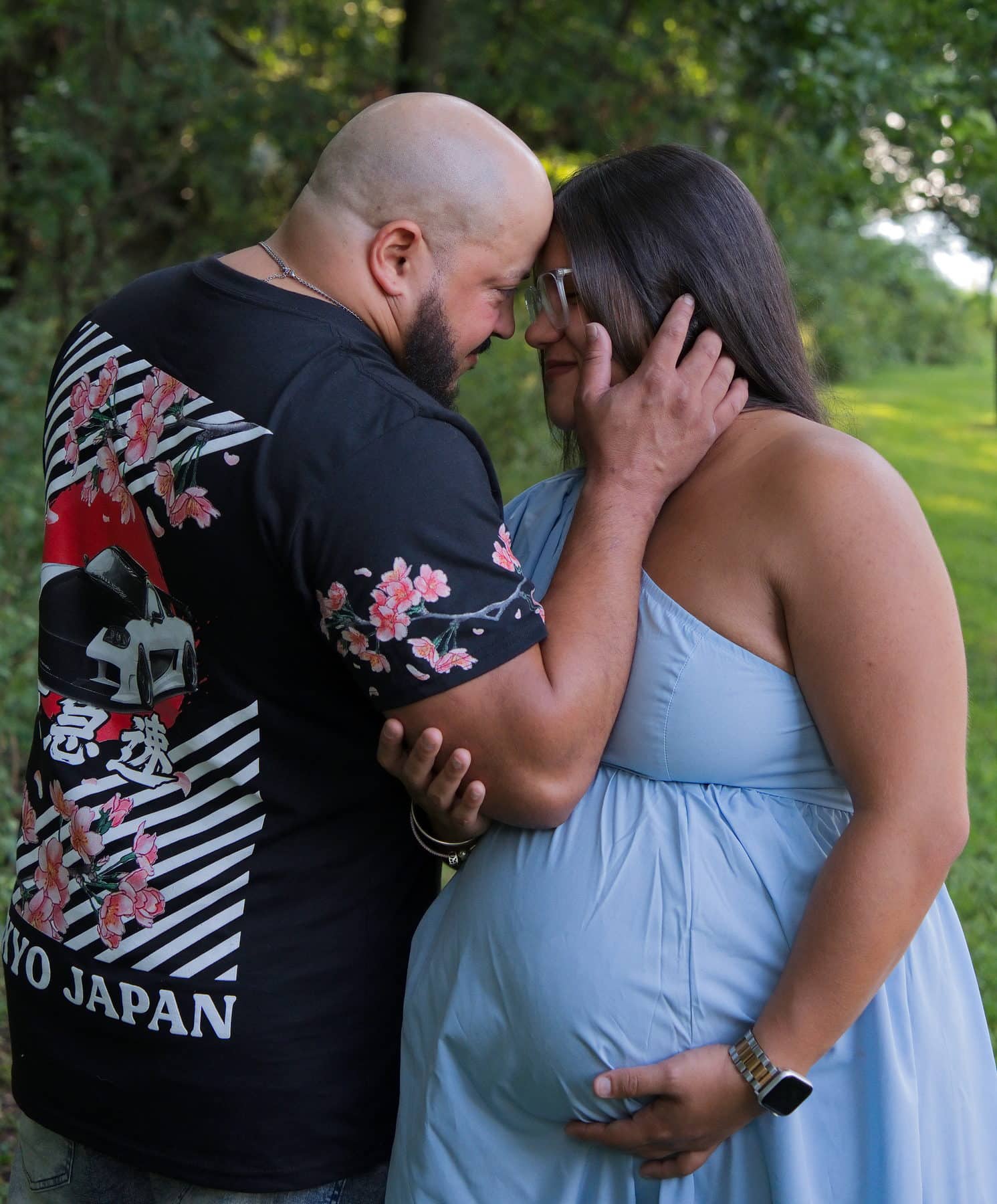 Expectant parents with their foreheads together, hands on the bump