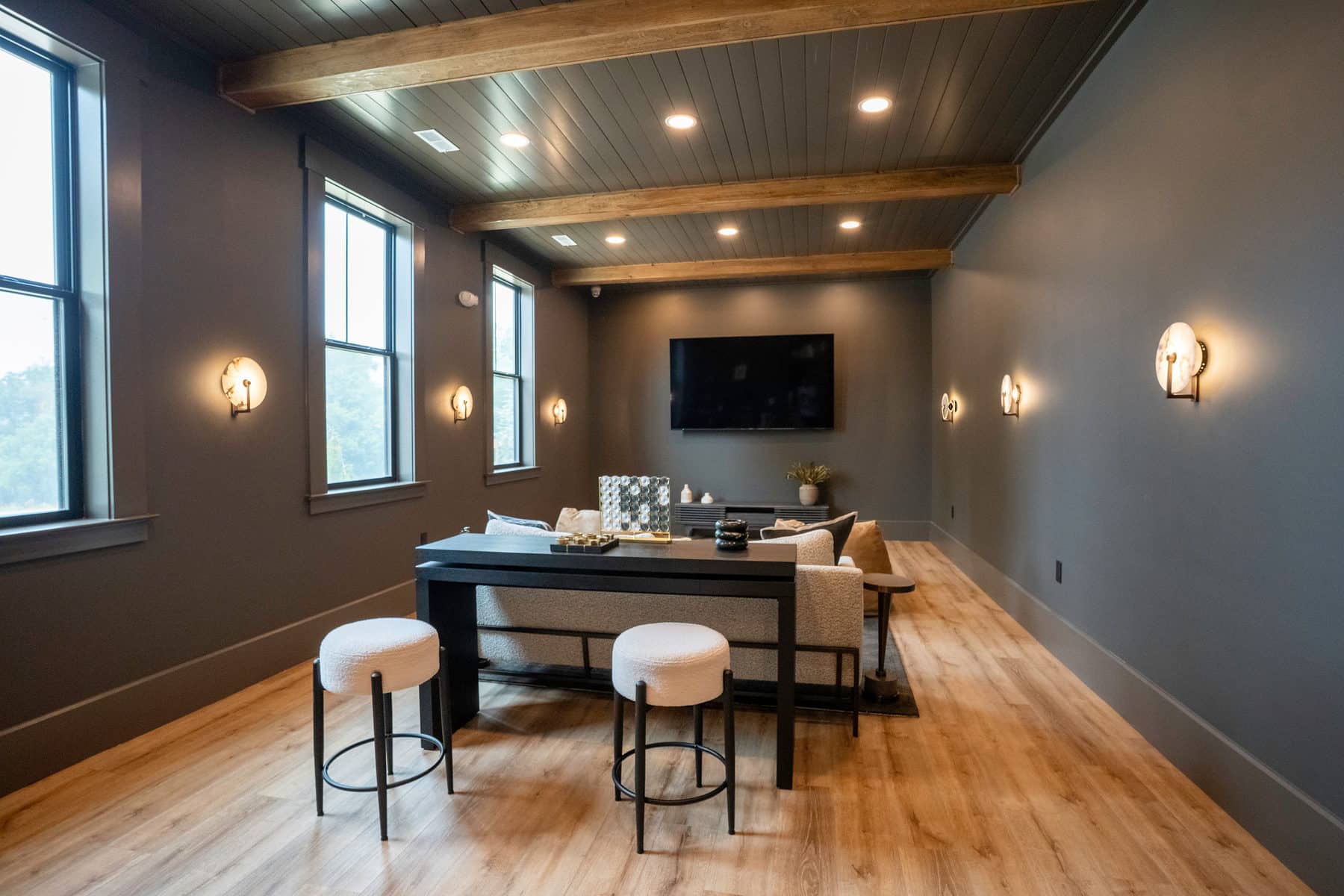 A clubhouse bar counter with white stools against a charcoal wall