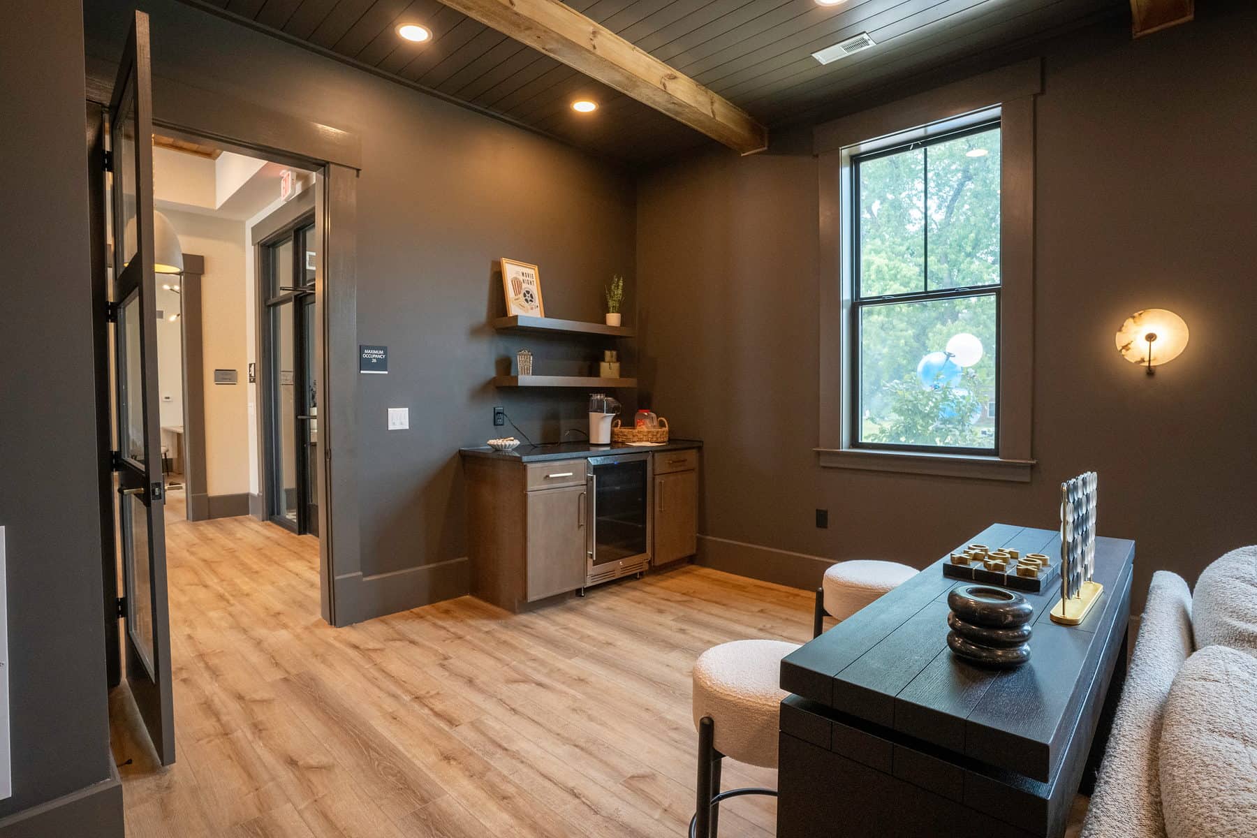 A clubhouse coffee bar with a dark counter and stools beside a window