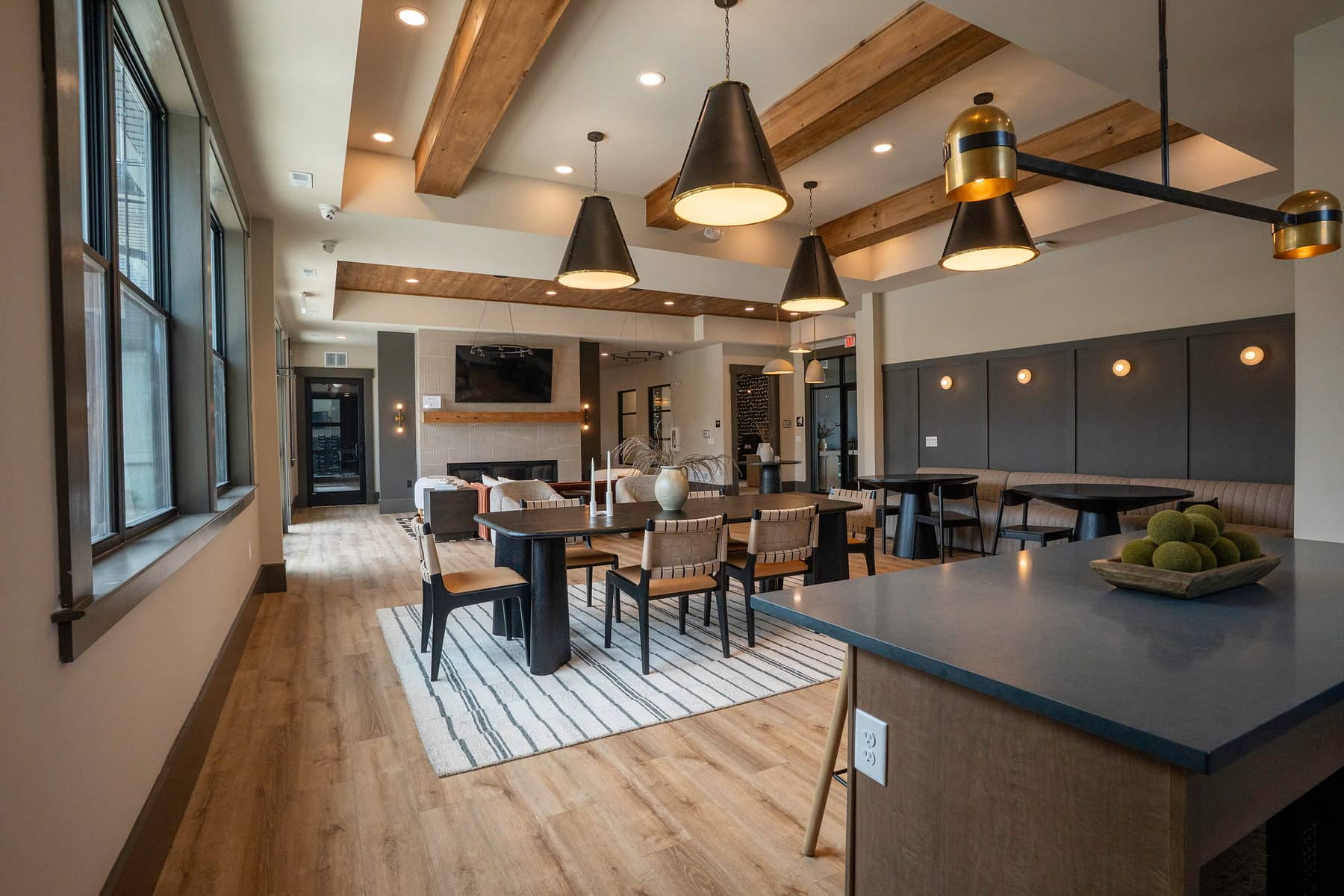 A long clubhouse dining run under exposed beams and black pendant lights
