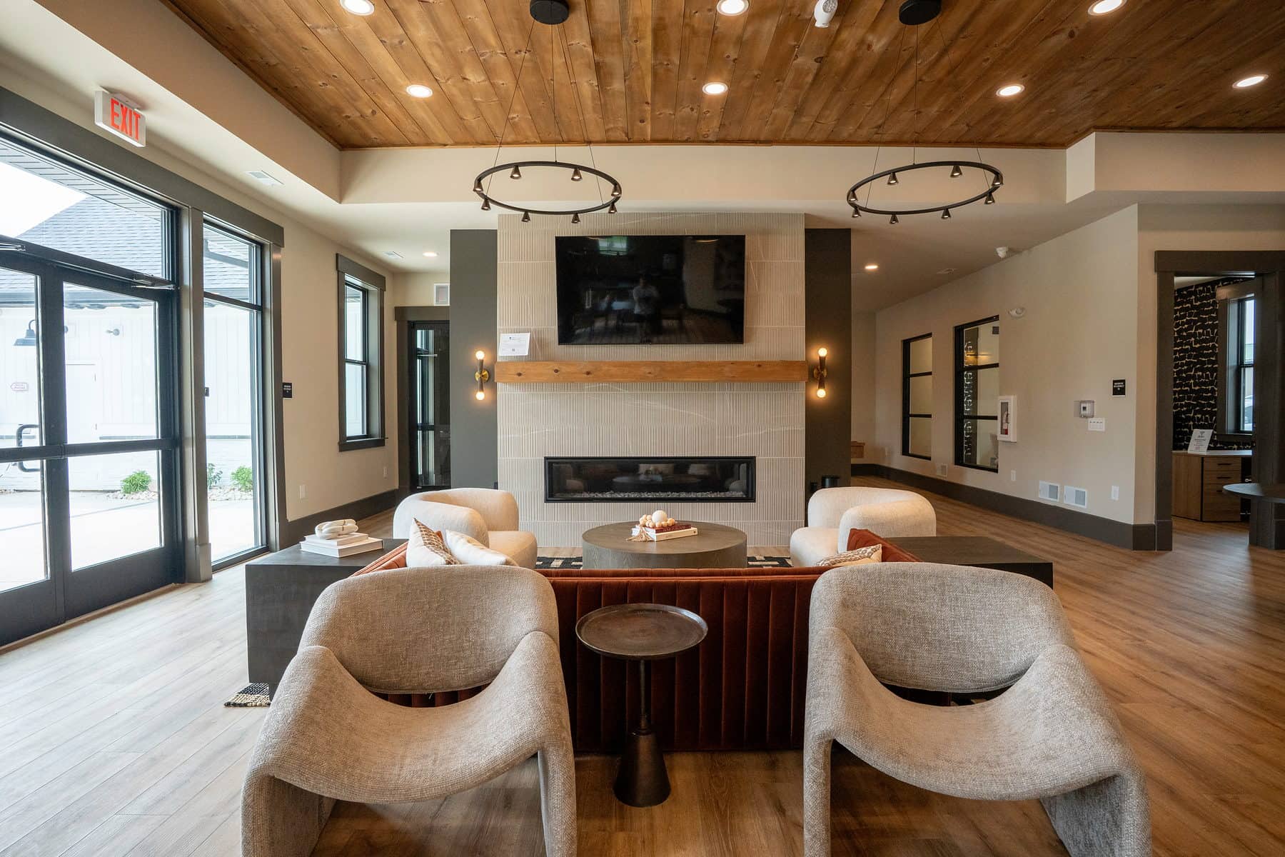 A clubhouse lounge with cream armchairs arranged around a linear fireplace