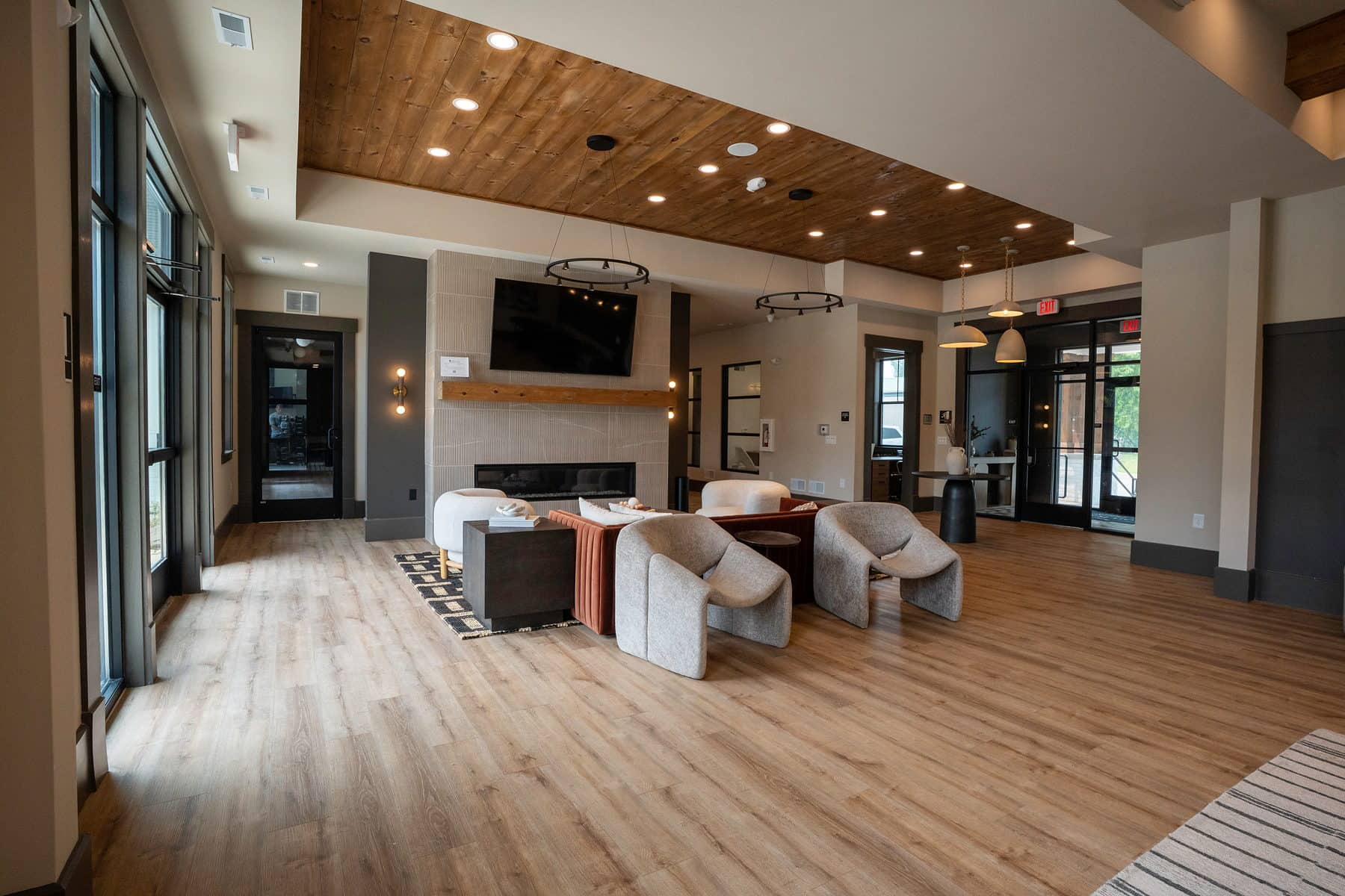 A clubhouse media lounge with a mounted screen, low seating and wood ceiling
