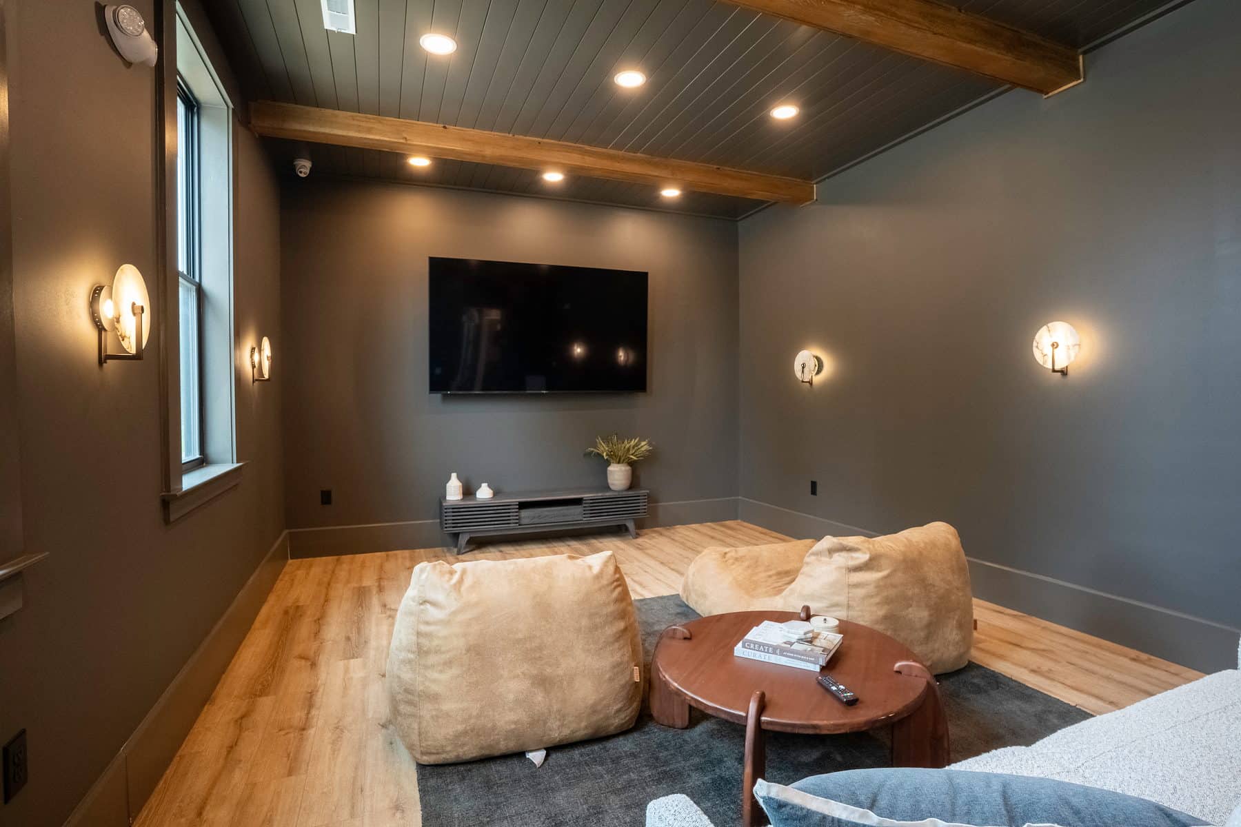 A dark clubhouse den with floor cushions and a mounted screen