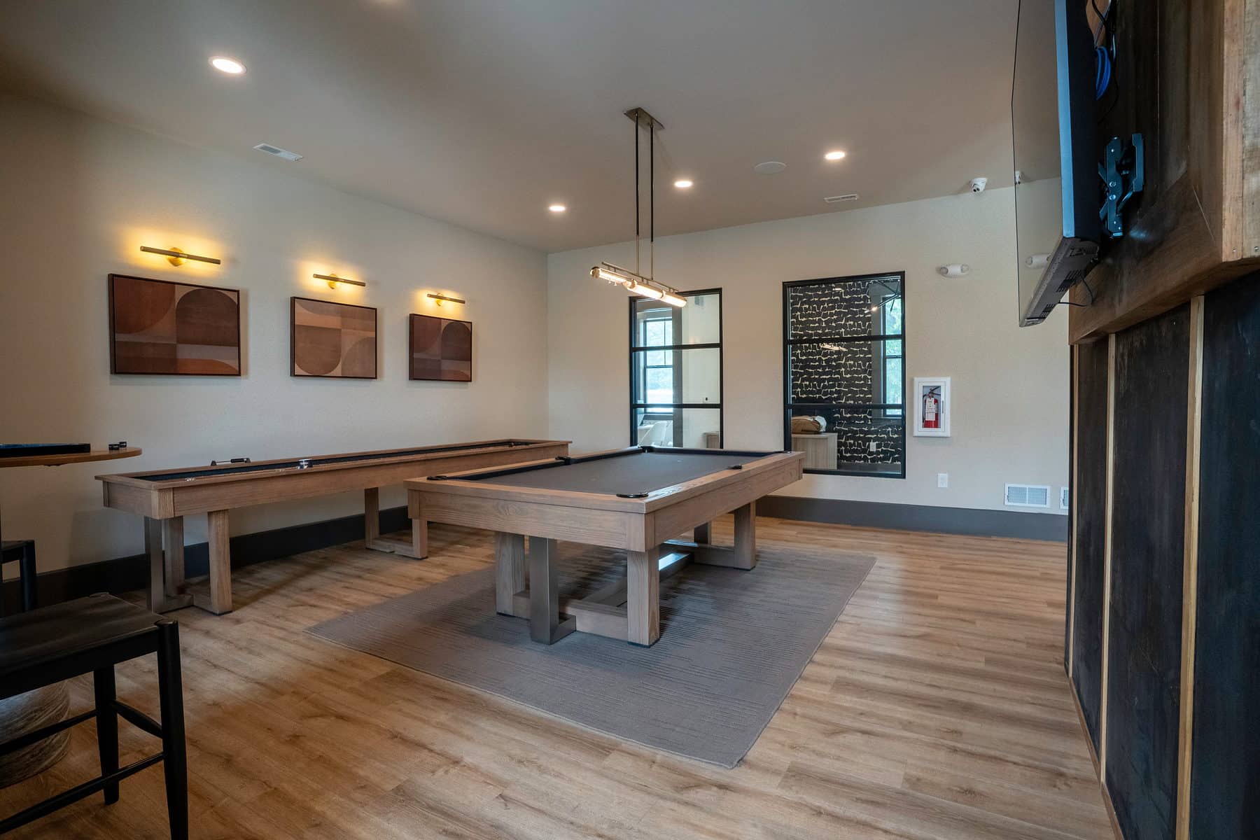 A community game room photographed wide with shuffleboard and pool table