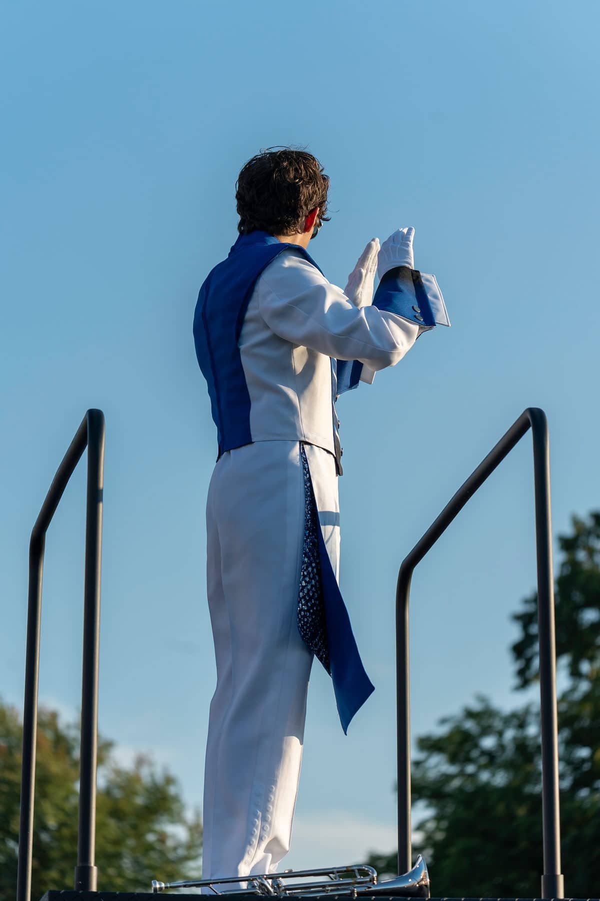 A drum major standing on the podium against an open sky before a performance