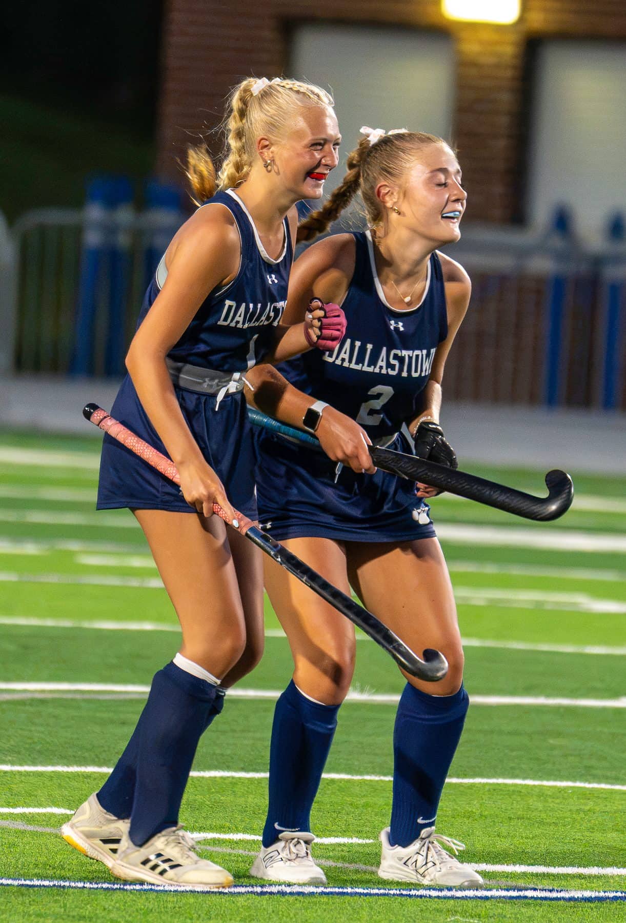 Two field hockey teammates walking off the turf together after a match