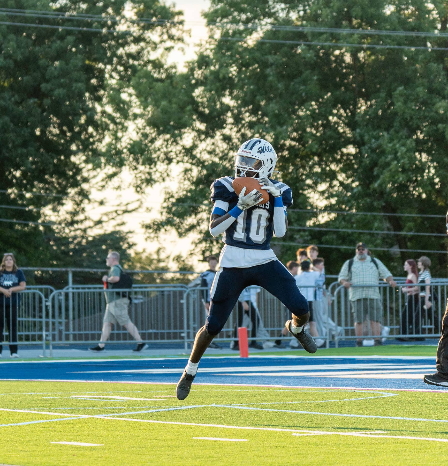 A high school football player leaping into the end zone with the ball