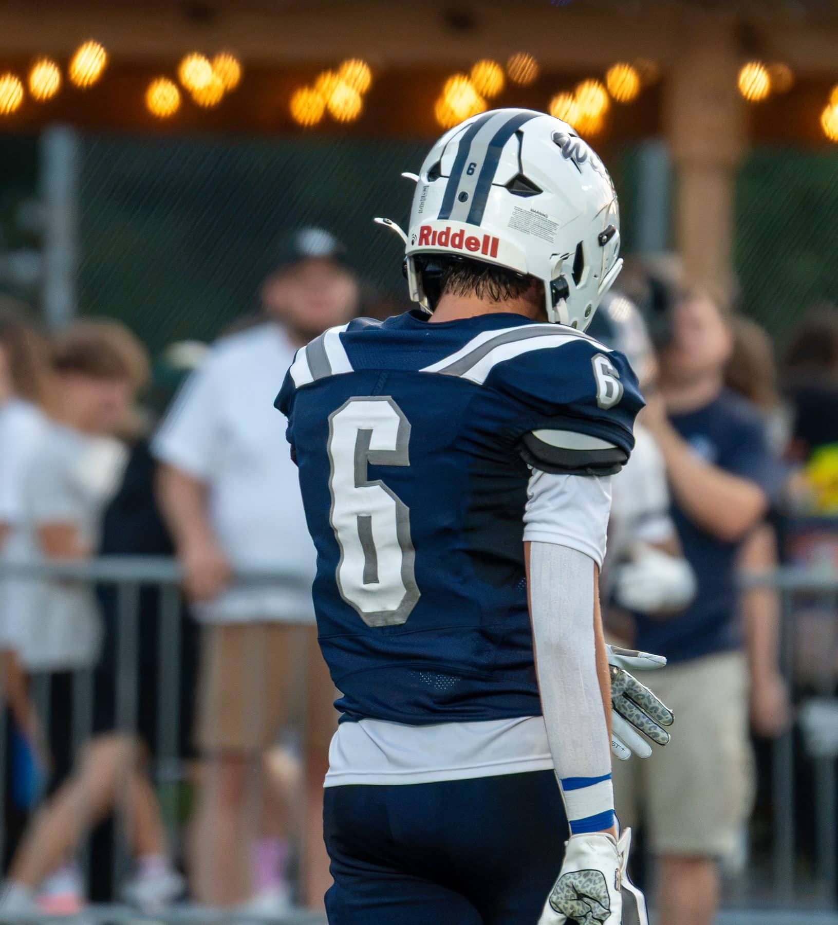 A high school football player on the sideline under the stadium lights