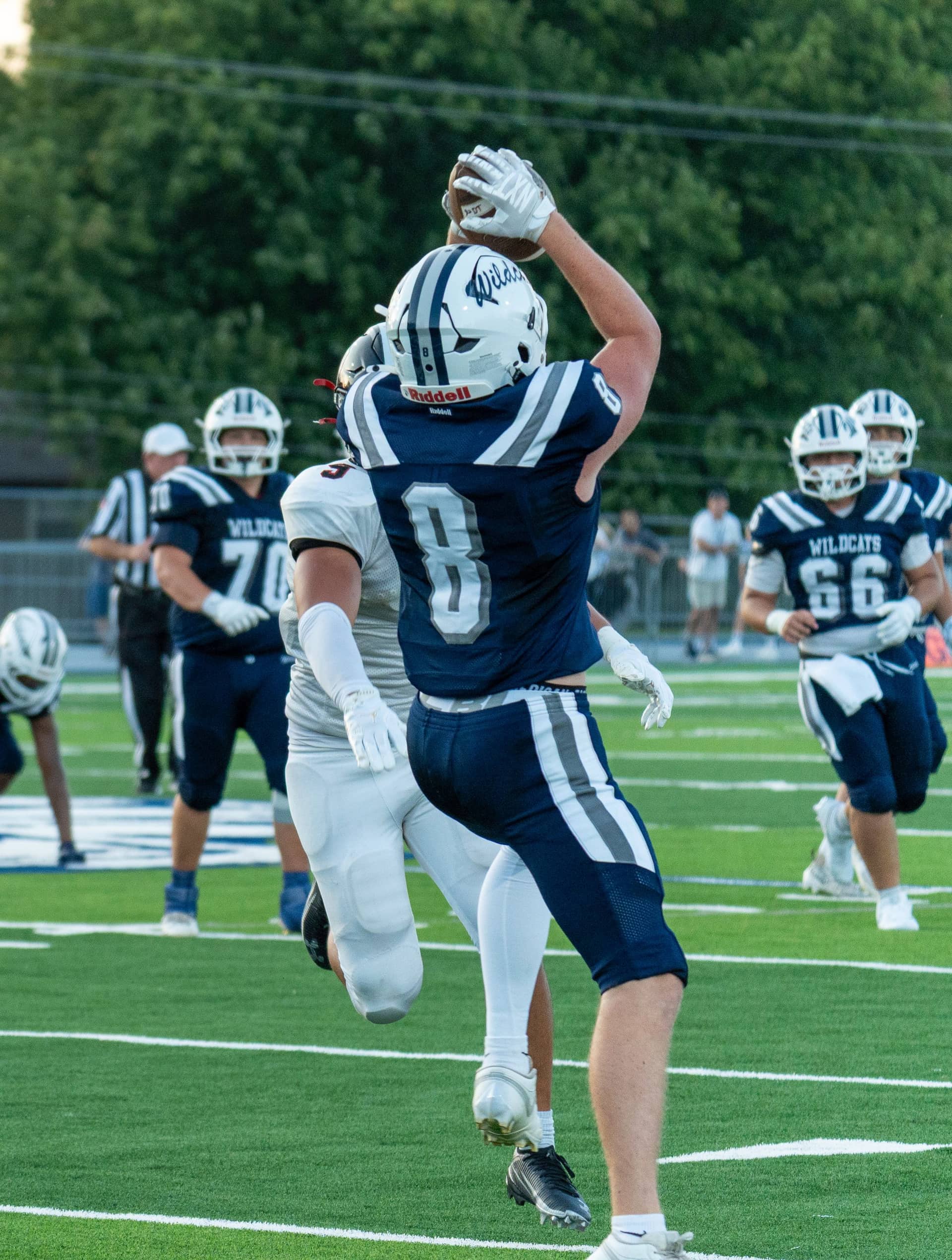 A receiver making a catch in traffic under stadium lights