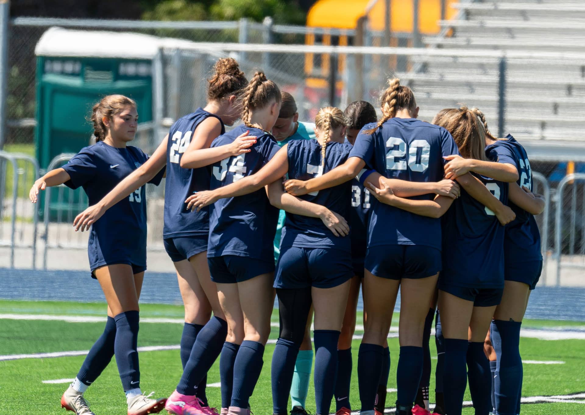 A high school girls soccer team in a pregame huddle