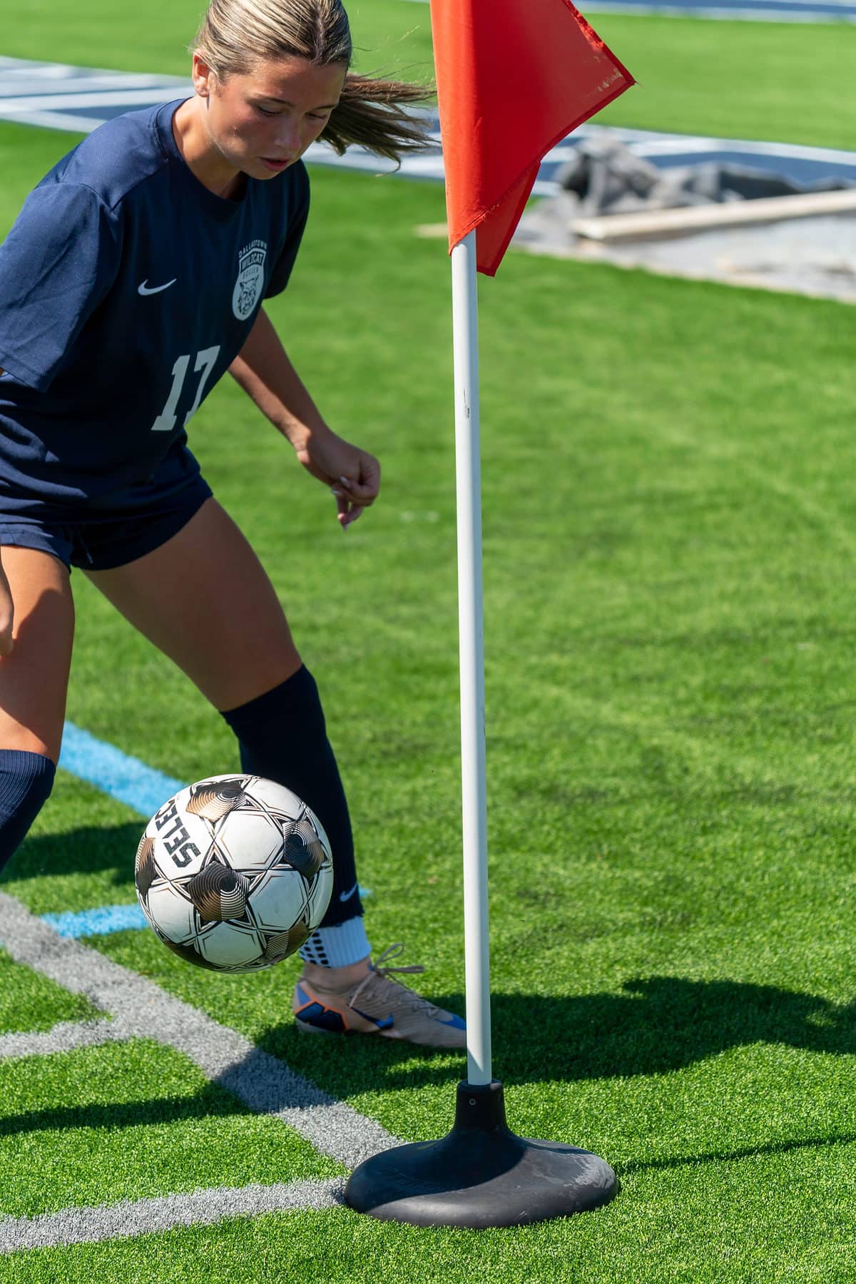 A soccer player driving the ball past the corner flag
