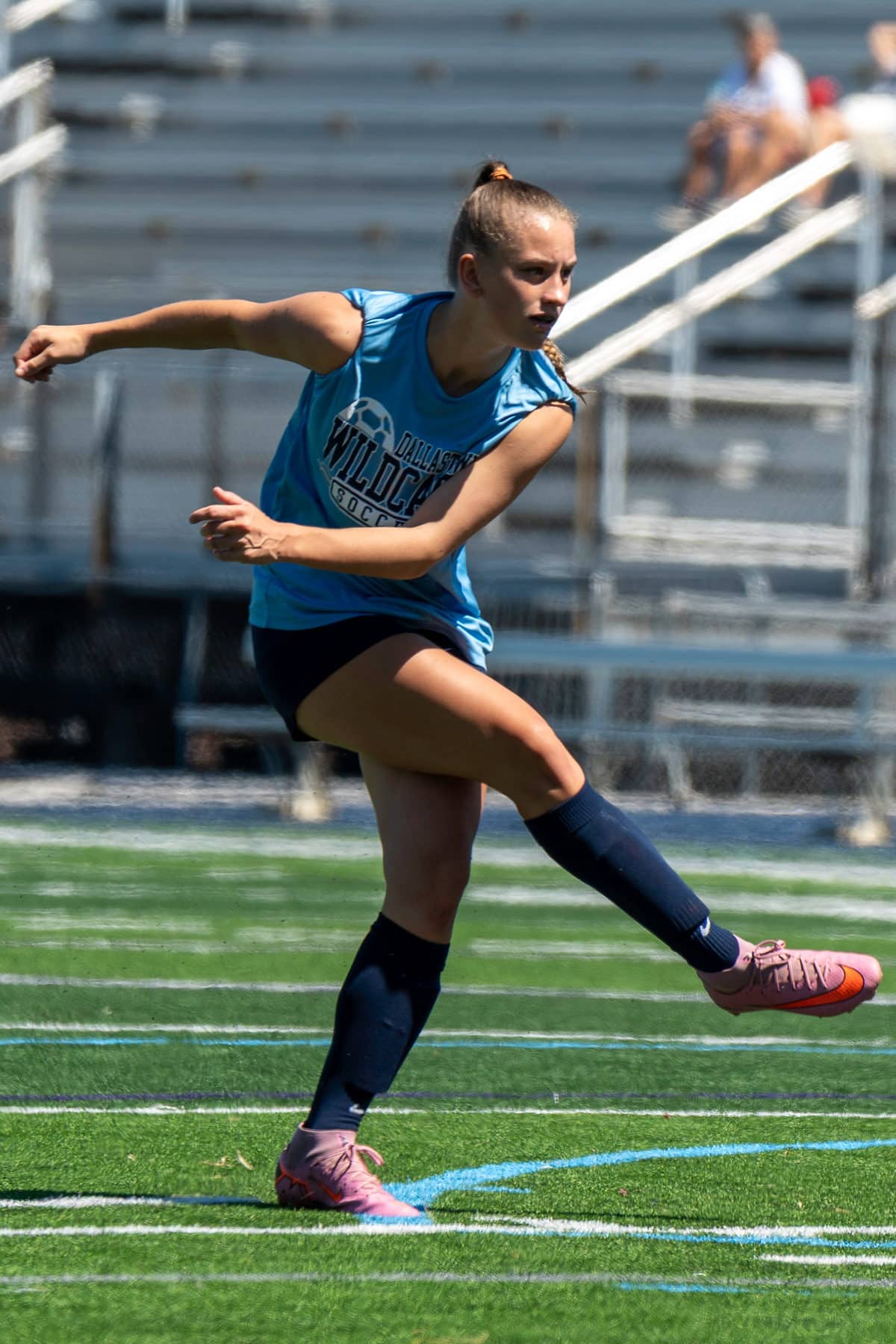A high school soccer player striking the ball with full extension