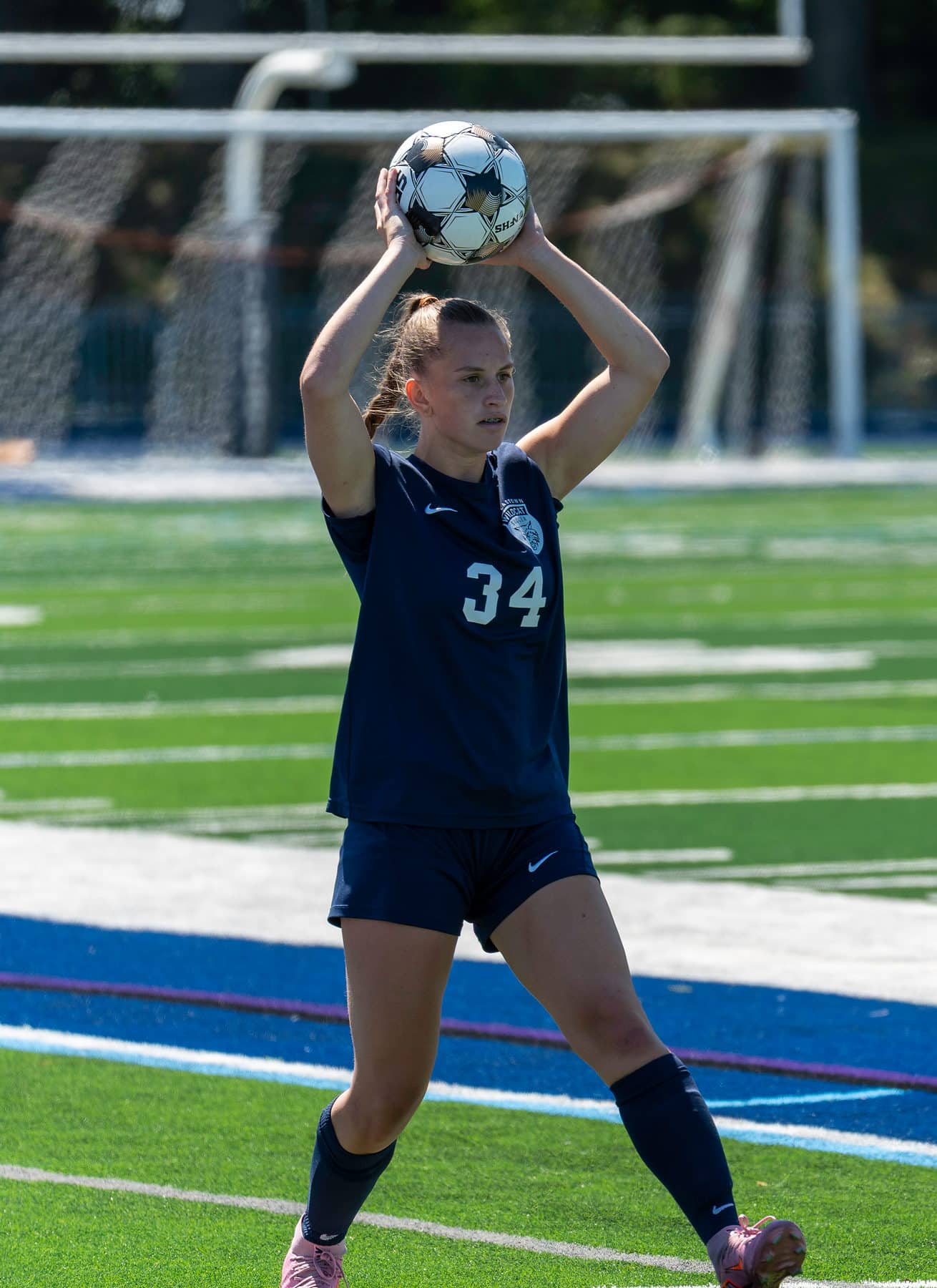 A high school soccer player taking a throw in with the ball overhead