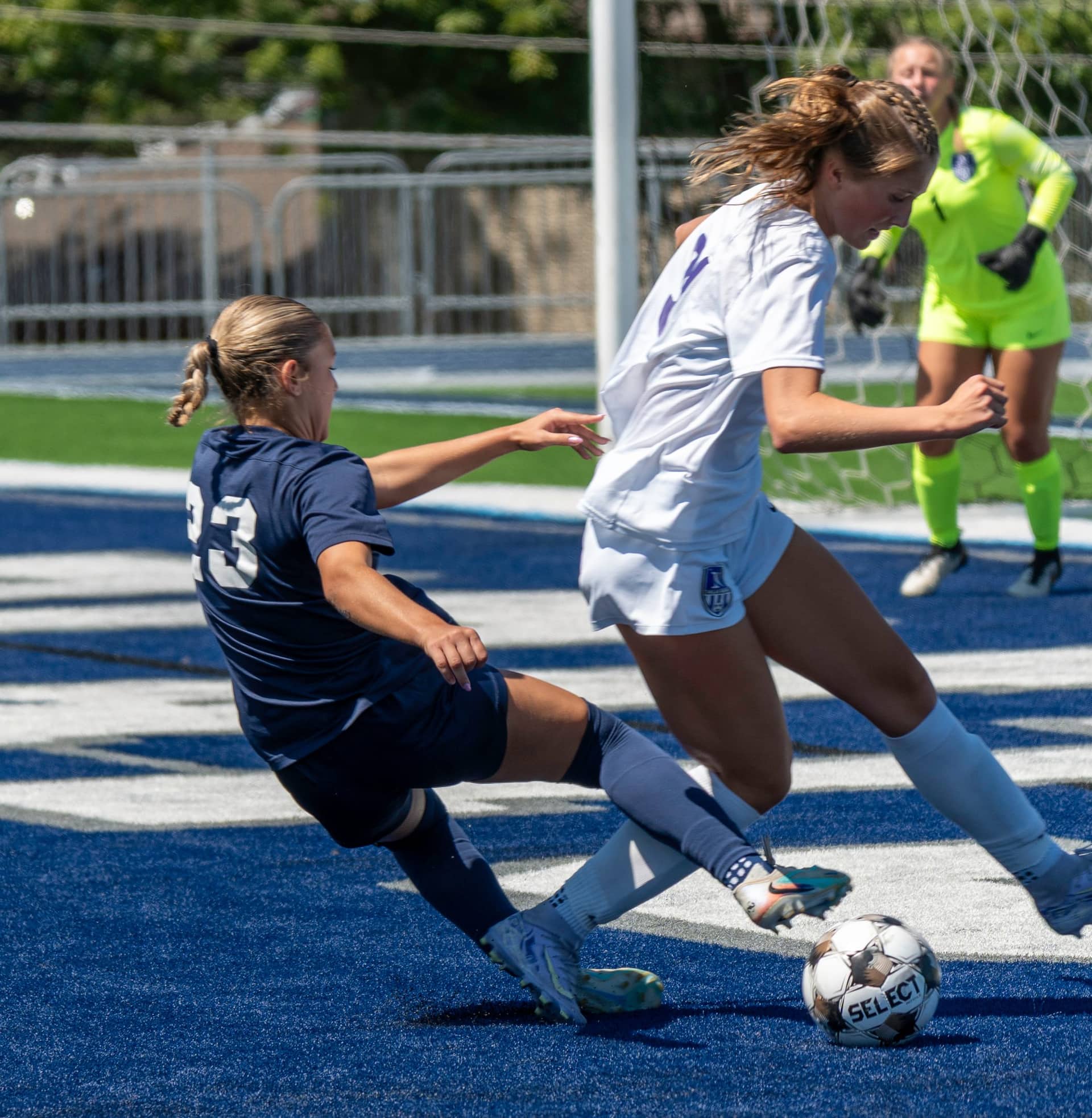 A defender sliding into a tackle during a soccer match