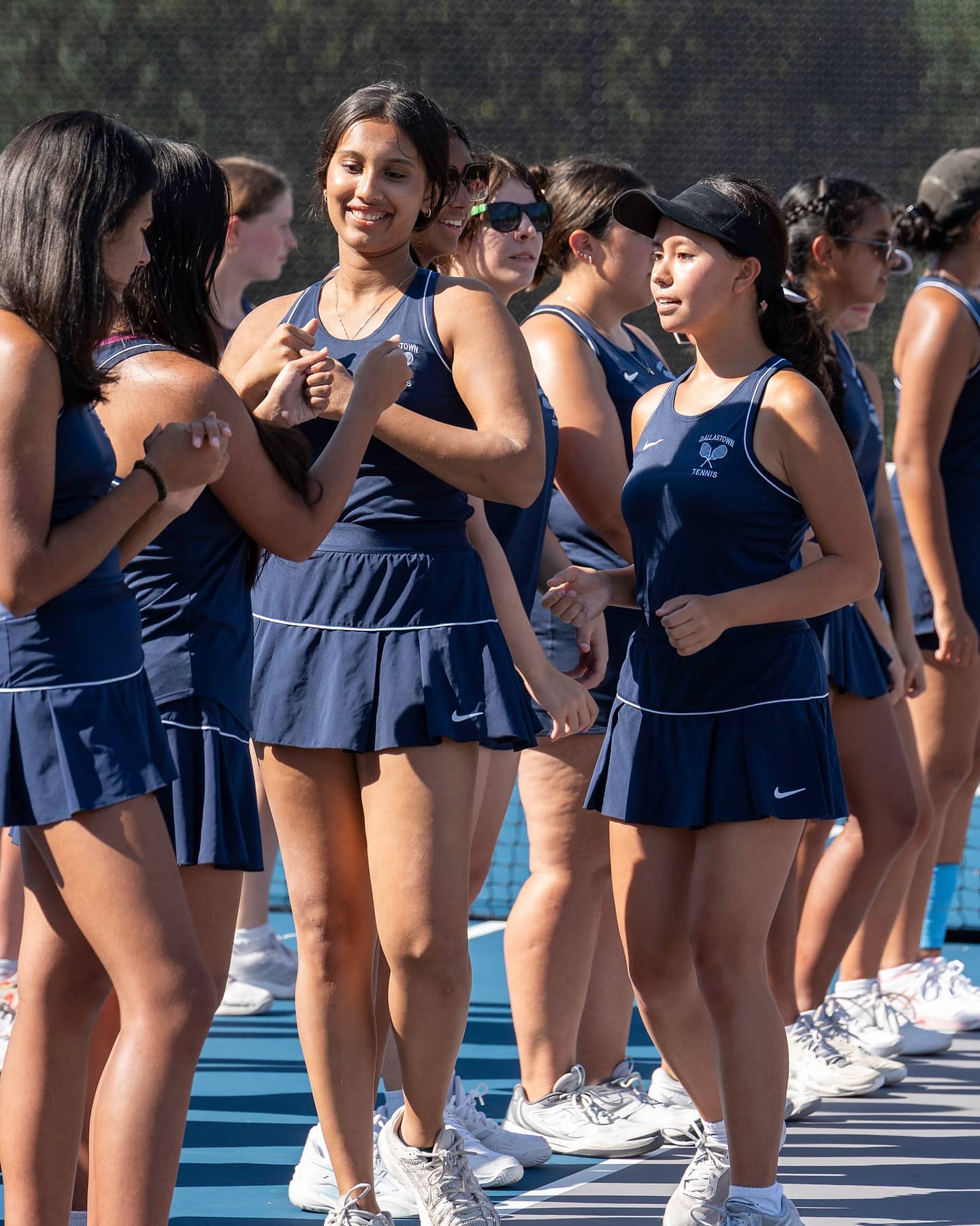 Two high school tennis teams shaking hands along the net after a match