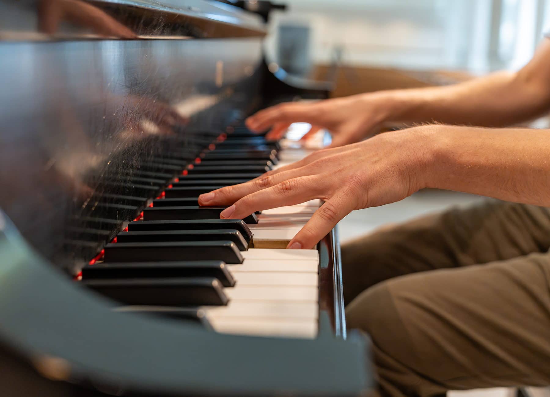 An accompanist's hands moving across the keys of a grand piano
