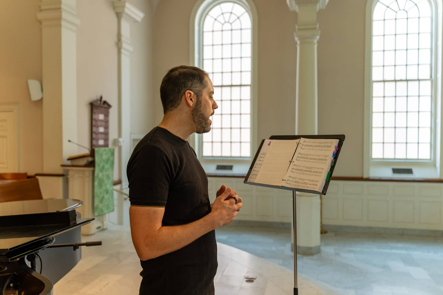 A singer reading through the score at a music stand in window light