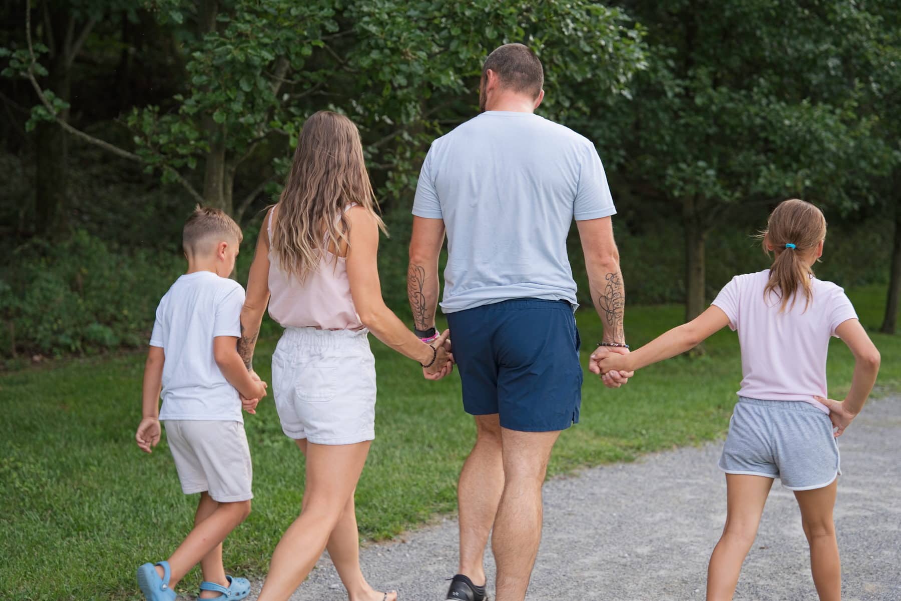 A family walking a gravel path at dusk with their children running ahead