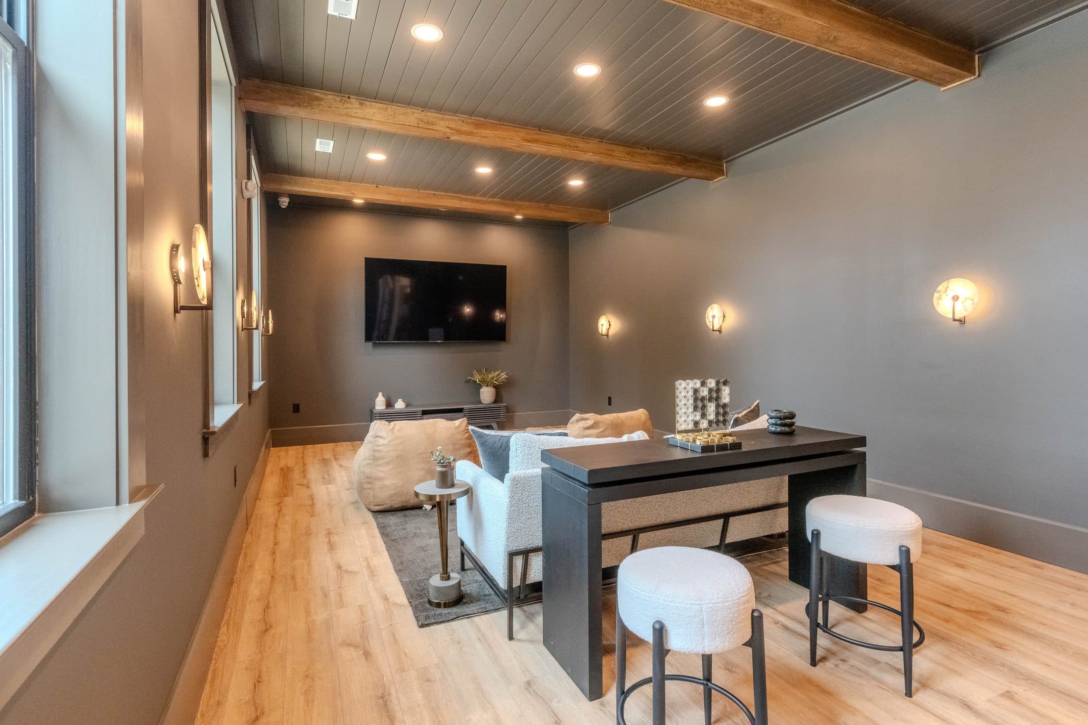 Community media lounge with charcoal walls and wood beams