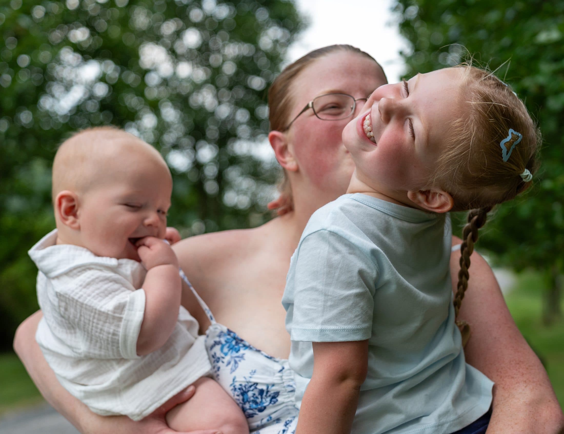 A mother laughing with her two children in warm evening light