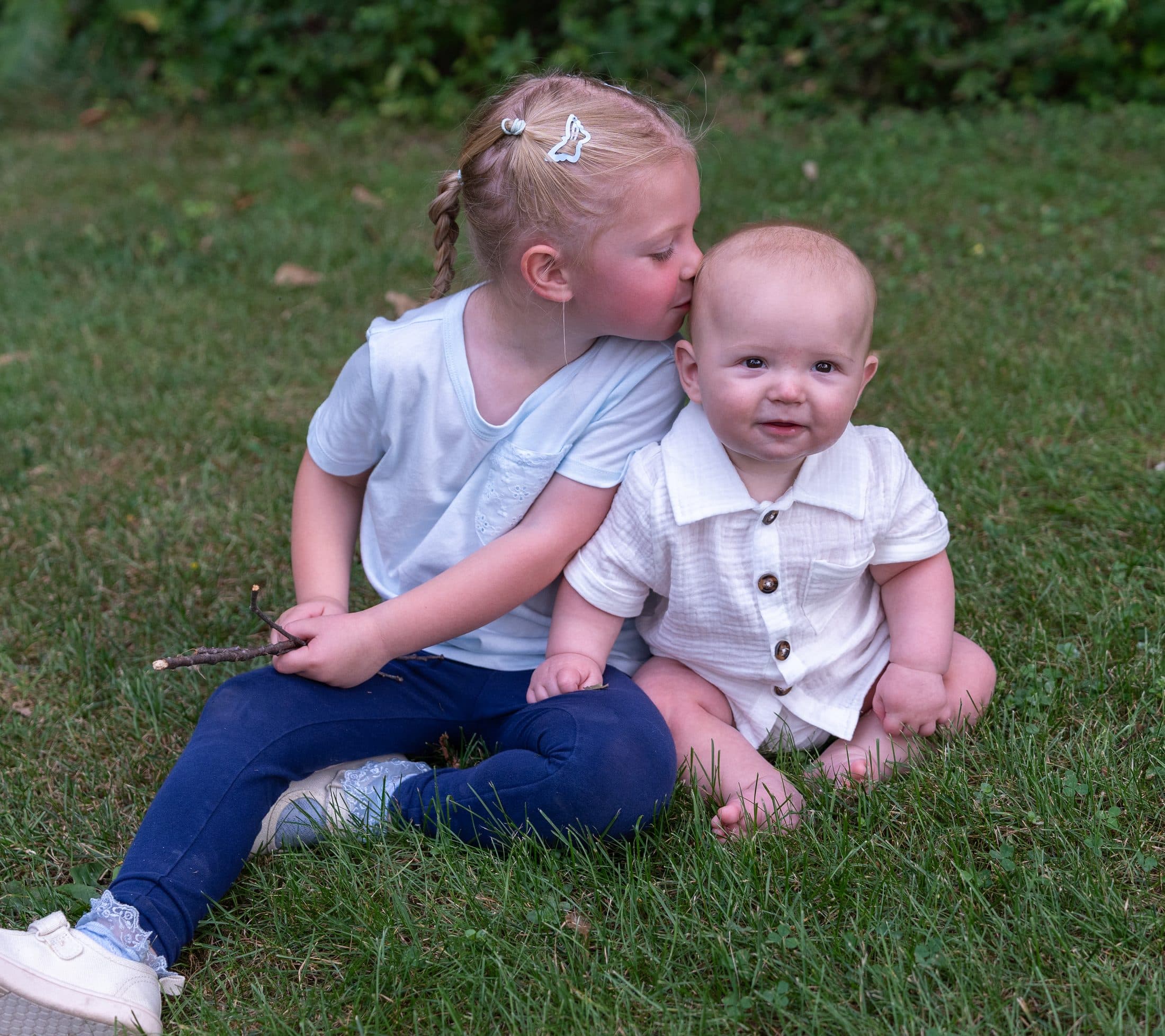 Two young siblings sitting together in soft blues and neutrals