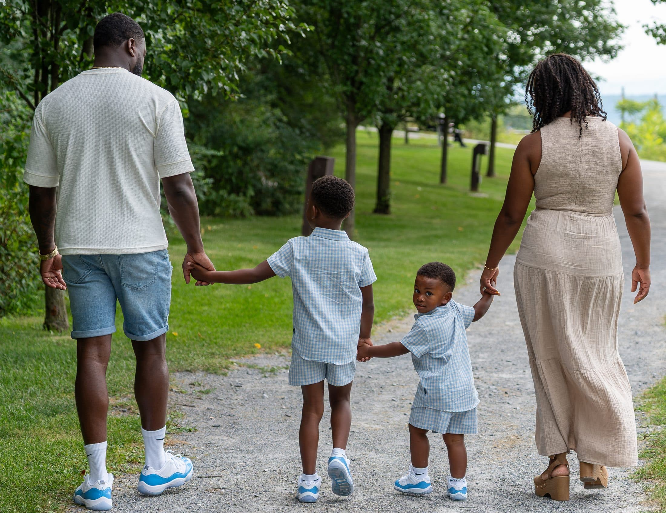 A family of four walking away down a gravel path in coordinated earth tones